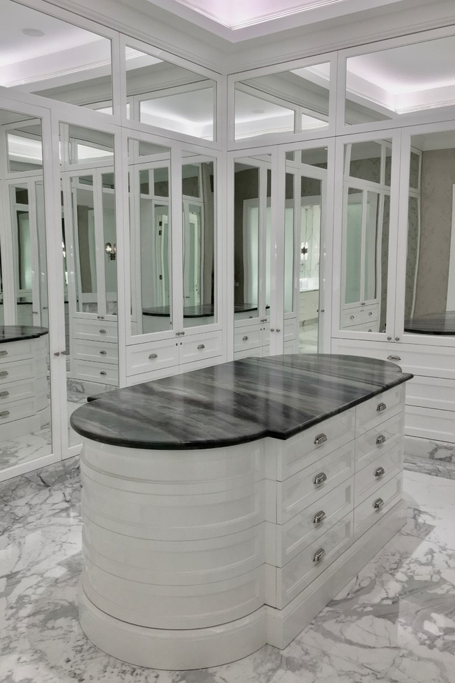 Aménagement d'un grand dressing neutre avec un placard avec porte à panneau encastré, des portes de placard blanches, un sol en marbre et un sol blanc.