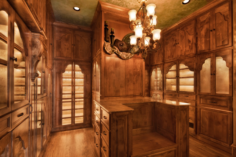 Idee per una cabina armadio unisex stile rurale di medie dimensioni con ante con bugna sagomata, ante in legno bruno e pavimento in legno massello medio
