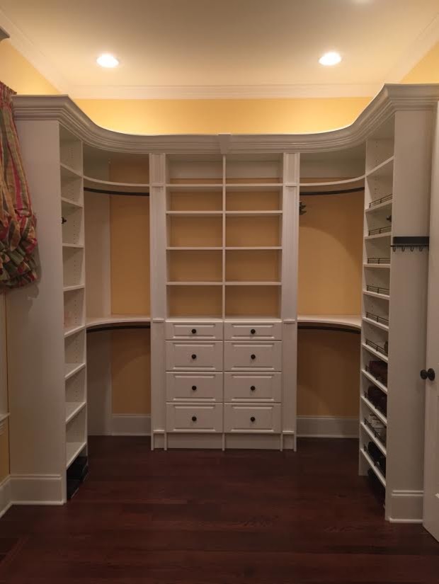 Foto de armario vestidor unisex clásico grande con armarios con paneles con relieve, puertas de armario blancas, suelo de madera oscura y suelo marrón