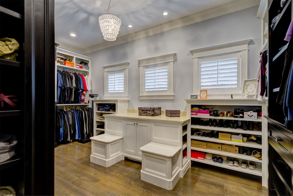 This is an example of a large traditional gender neutral dressing room in Chicago with shaker cabinets, black cabinets, medium hardwood flooring and brown floors.
