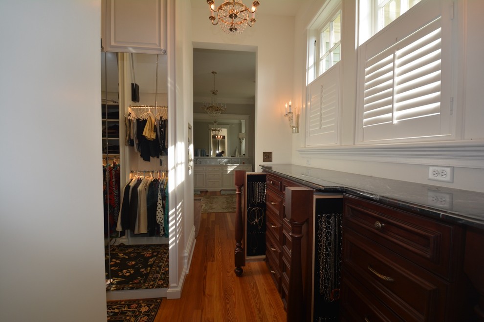 Diseño de vestidor unisex clásico renovado grande con armarios con paneles empotrados, puertas de armario de madera en tonos medios y suelo de madera clara