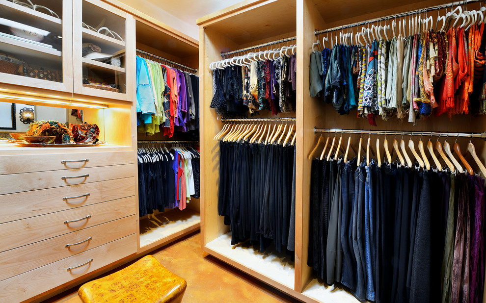 Diseño de armario vestidor de mujer tradicional renovado grande con puertas de armario de madera clara, suelo de cemento y armarios con paneles lisos