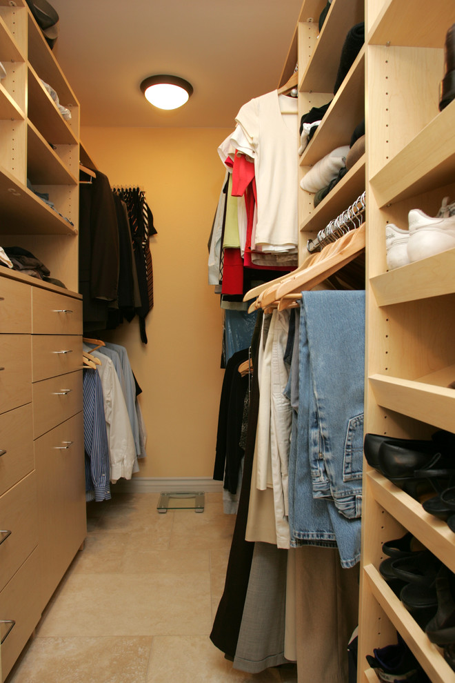 Ejemplo de armario vestidor unisex actual de tamaño medio con armarios con paneles lisos, puertas de armario de madera clara, suelo de travertino y suelo beige