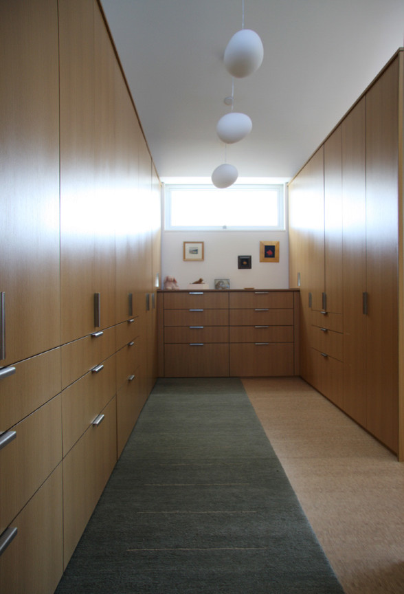 Пример оригинального дизайна: большая гардеробная комната унисекс в стиле модернизм с плоскими фасадами и фасадами цвета дерева среднего тона