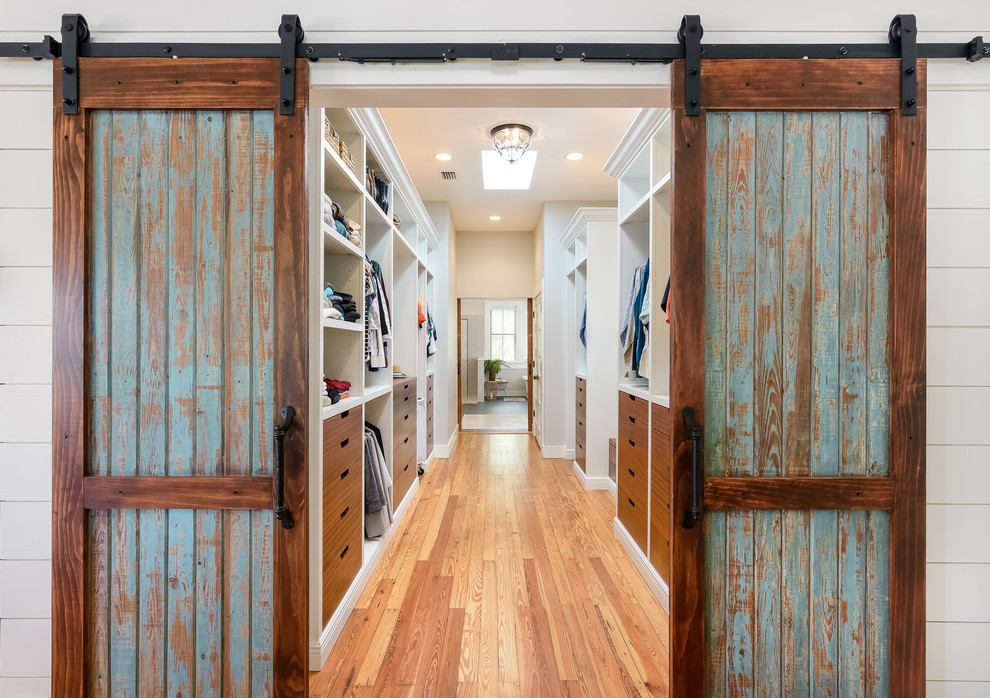 Ejemplo de armario vestidor unisex costero grande con armarios con paneles lisos, puertas de armario de madera oscura, suelo de madera en tonos medios y suelo marrón