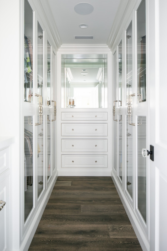Diseño de armario vestidor costero con armarios con rebordes decorativos, puertas de armario blancas, suelo de madera oscura y suelo marrón