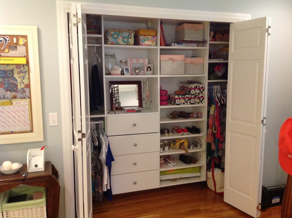 Foto de armario unisex clásico pequeño con armarios con paneles lisos, puertas de armario blancas, suelo de madera en tonos medios y suelo marrón