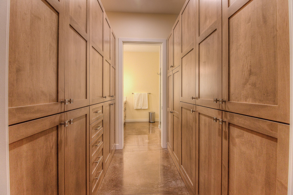 Elegant gender-neutral concrete floor and brown floor built-in closet photo in Other with shaker cabinets and medium tone wood cabinets