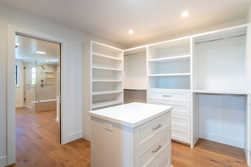 Expansive classic dressing room in Los Angeles with recessed-panel cabinets, white cabinets and medium hardwood flooring.
