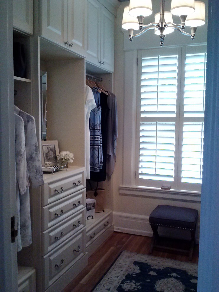 Diseño de armario vestidor de mujer tradicional extra grande con armarios con paneles con relieve, puertas de armario beige y suelo de madera clara