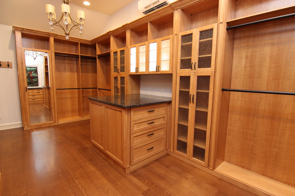 Walk-in closet - large traditional walk-in closet idea in Other with glass-front cabinets and medium tone wood cabinets