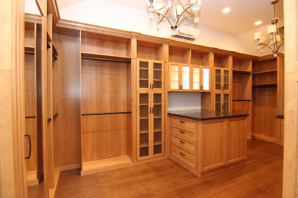 Diseño de armario vestidor clásico grande con armarios tipo vitrina y puertas de armario de madera oscura