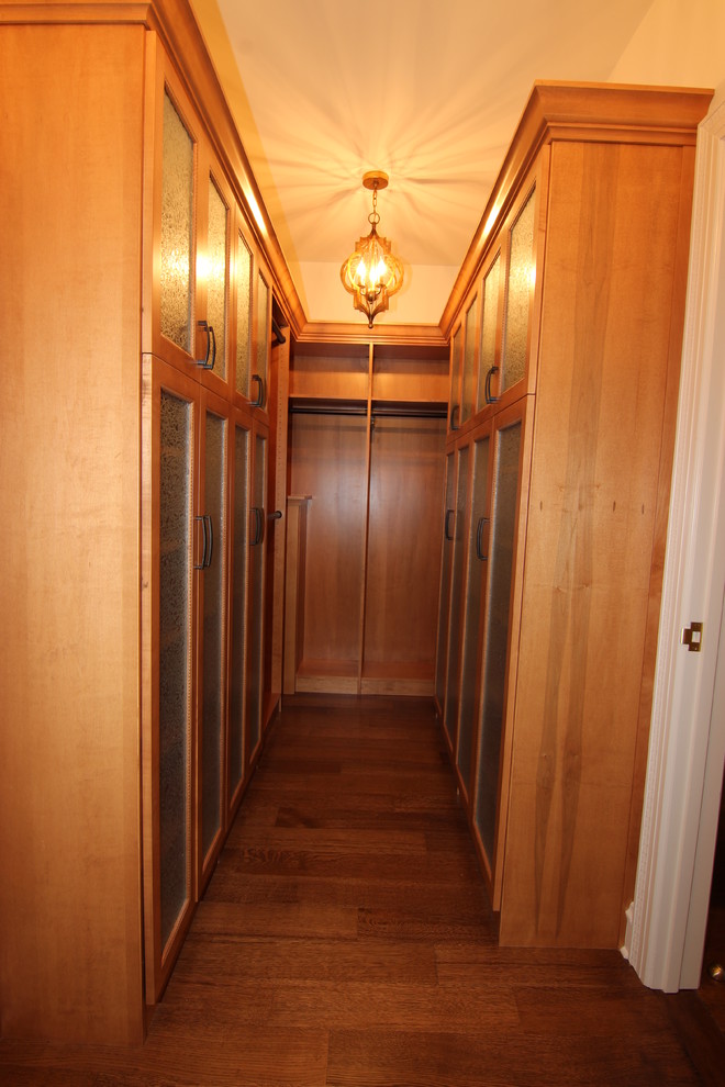 Cette image montre un grand dressing traditionnel en bois brun avec un placard à porte vitrée.