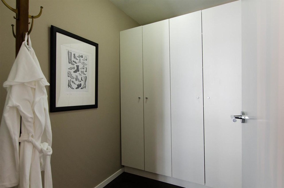 Photo of a small contemporary gender neutral walk-in wardrobe in Vancouver with flat-panel cabinets, white cabinets and dark hardwood flooring.