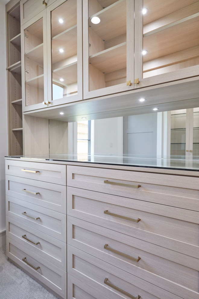 Modelo de armario vestidor unisex campestre grande con armarios estilo shaker, puertas de armario de madera clara, moqueta y suelo beige