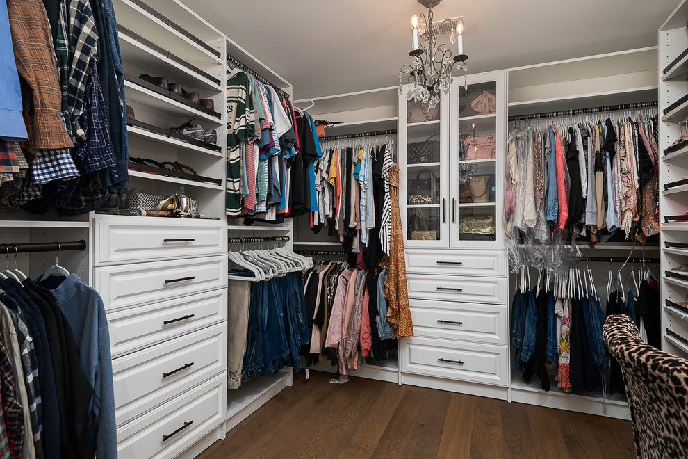 Medium sized country gender neutral walk-in wardrobe in Other with raised-panel cabinets, white cabinets, medium hardwood flooring and brown floors.