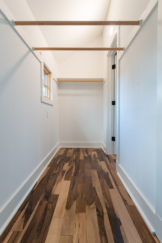 Lantlig inredning av ett litet walk-in-closet för könsneutrala, med mellanmörkt trägolv och brunt golv