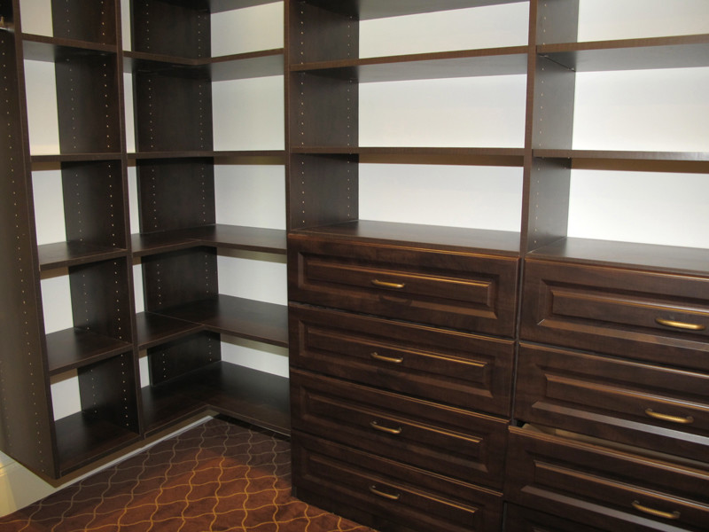 Example of a mid-sized classic gender-neutral carpeted walk-in closet design in New York with raised-panel cabinets and brown cabinets