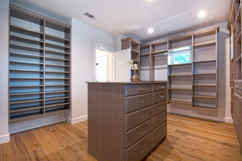Inspiration for a large classic gender neutral walk-in wardrobe in Los Angeles with dark wood cabinets, flat-panel cabinets, medium hardwood flooring and brown floors.