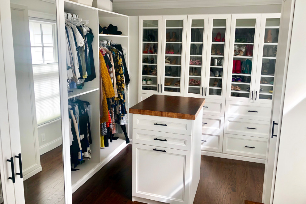 This is an example of a medium sized traditional gender neutral walk-in wardrobe in New York with raised-panel cabinets, white cabinets, dark hardwood flooring and brown floors.