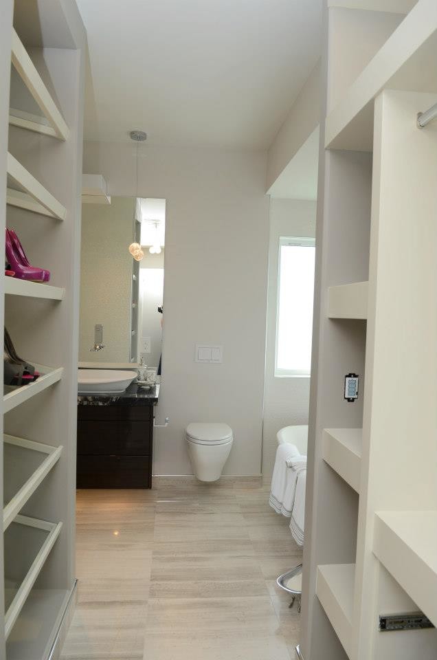 Large modern wardrobe in Other with flat-panel cabinets, dark wood cabinets and travertine flooring.