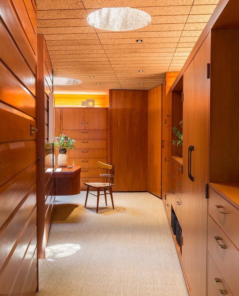 Immagine di uno spazio per vestirsi unisex minimalista con ante lisce, ante in legno scuro, moquette, pavimento beige e soffitto in legno