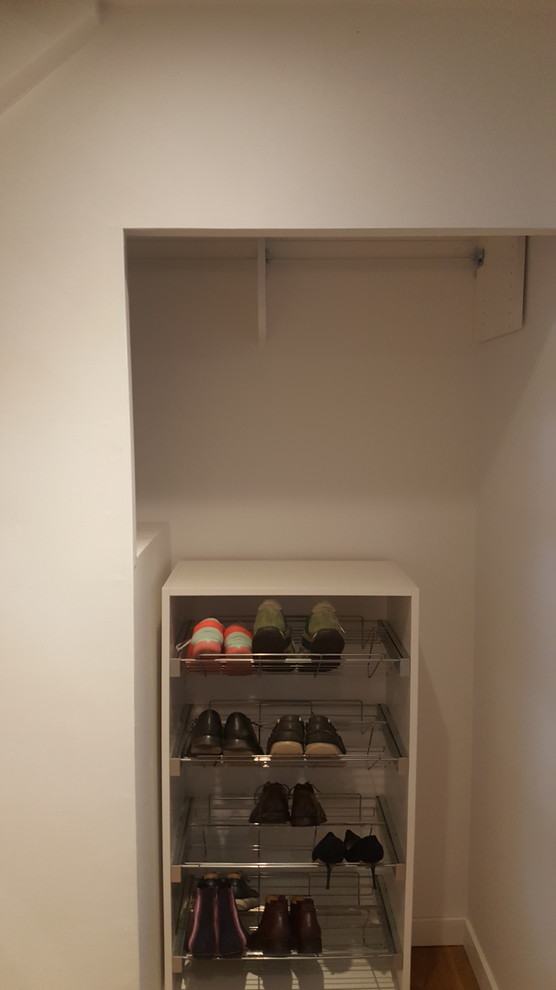 Modelo de armario unisex minimalista pequeño con armarios con paneles lisos, puertas de armario blancas, suelo laminado y suelo marrón