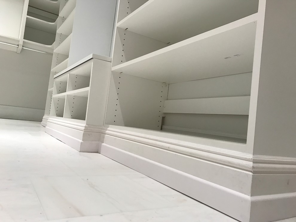 Diseño de armario vestidor unisex tradicional grande con puertas de armario blancas y suelo de mármol