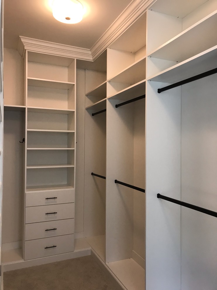 This is an example of a medium sized traditional gender neutral walk-in wardrobe in DC Metro with flat-panel cabinets, white cabinets, carpet and beige floors.