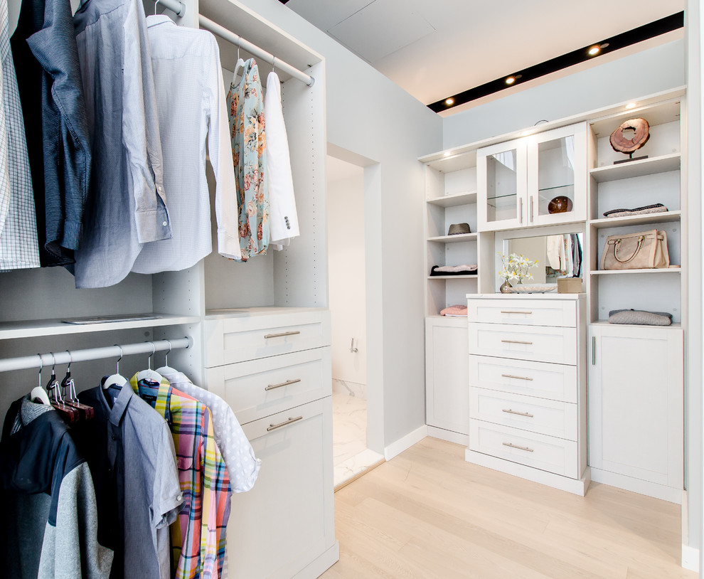 Modelo de armario unisex moderno pequeño con puertas de armario blancas y suelo de madera en tonos medios