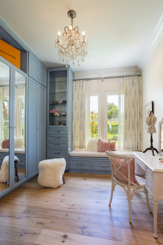 Photo of a traditional dressing room for women in Orange County with shaker cabinets, blue cabinets, medium hardwood flooring and brown floors.