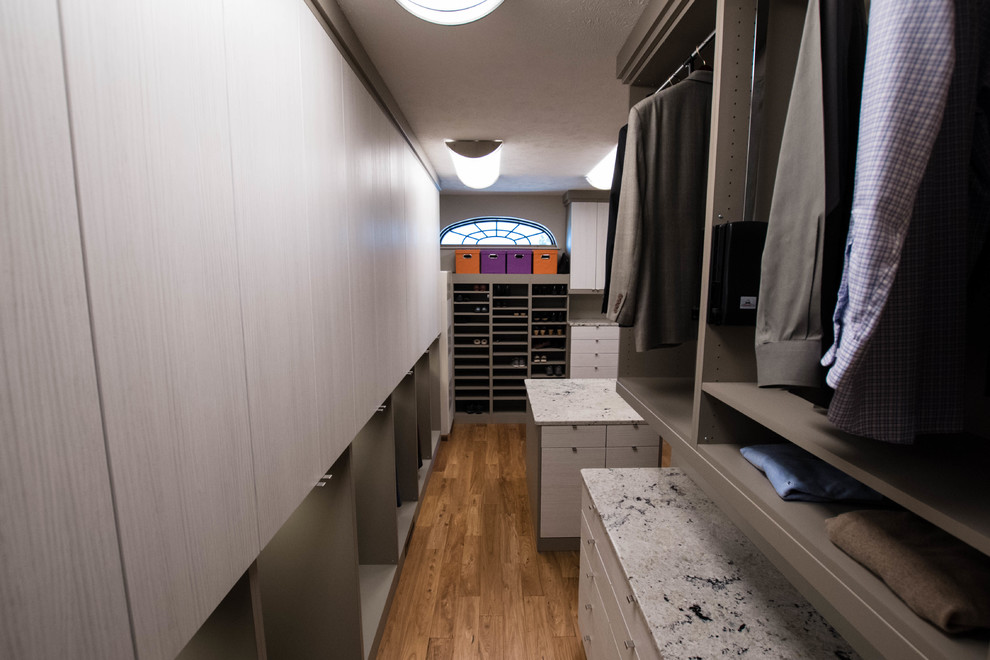 Modelo de armario vestidor unisex actual grande con armarios con paneles lisos y suelo de madera en tonos medios