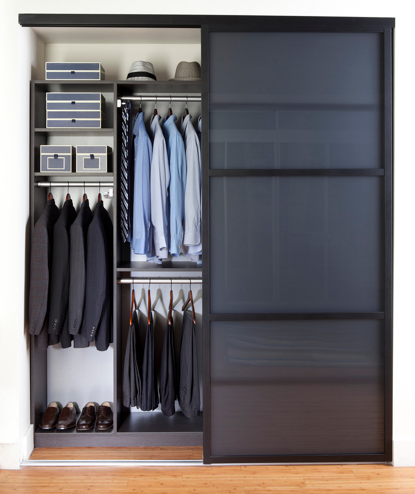 Exemple d'un placard dressing tendance neutre et de taille moyenne avec parquet clair et des portes de placard grises.