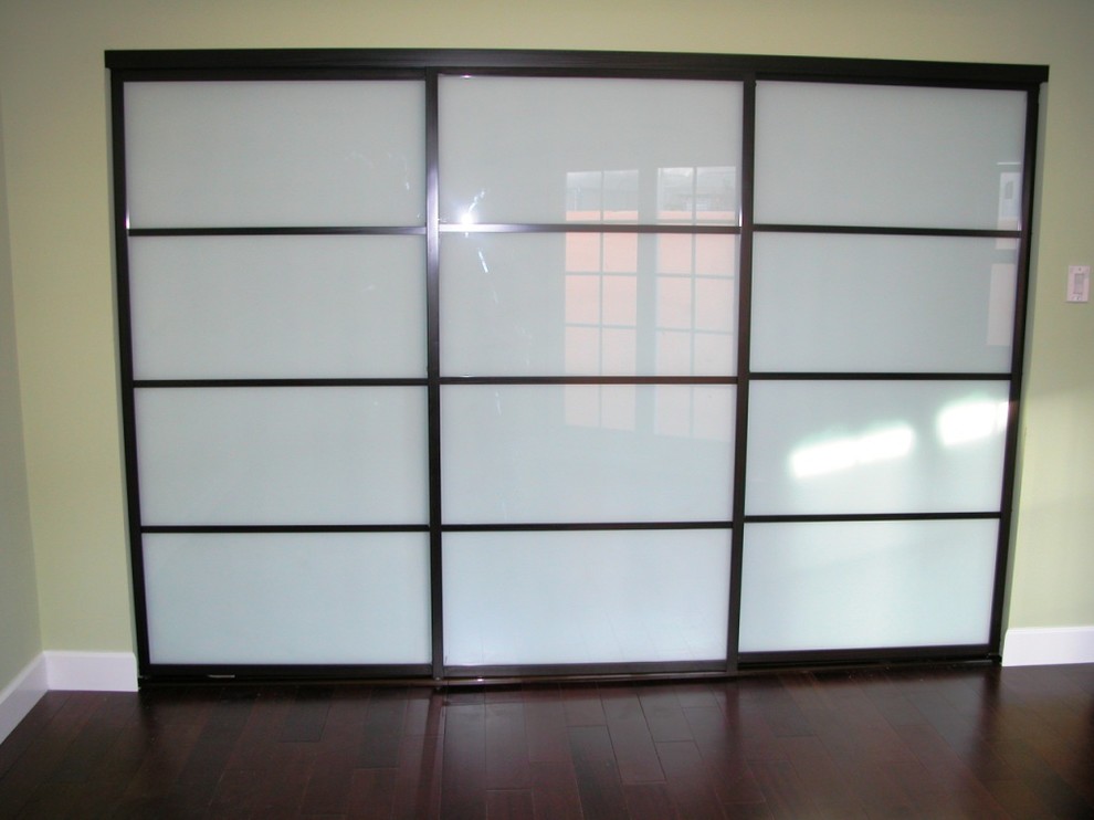 Cette image montre un placard dressing design de taille moyenne et neutre avec un placard à porte plane, parquet foncé et un sol marron.