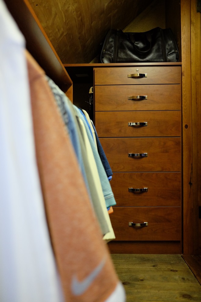 Imagen de armario vestidor de hombre actual pequeño con armarios con paneles lisos, puertas de armario de madera oscura y suelo de madera clara