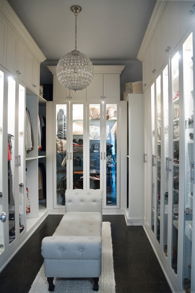 На фото: гардеробная комната среднего размера в стиле неоклассика (современная классика) с стеклянными фасадами, белыми фасадами, темным паркетным полом и коричневым полом для женщин с
