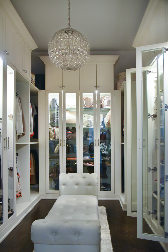 На фото: гардеробная комната среднего размера в стиле неоклассика (современная классика) с стеклянными фасадами, белыми фасадами, темным паркетным полом и коричневым полом для женщин