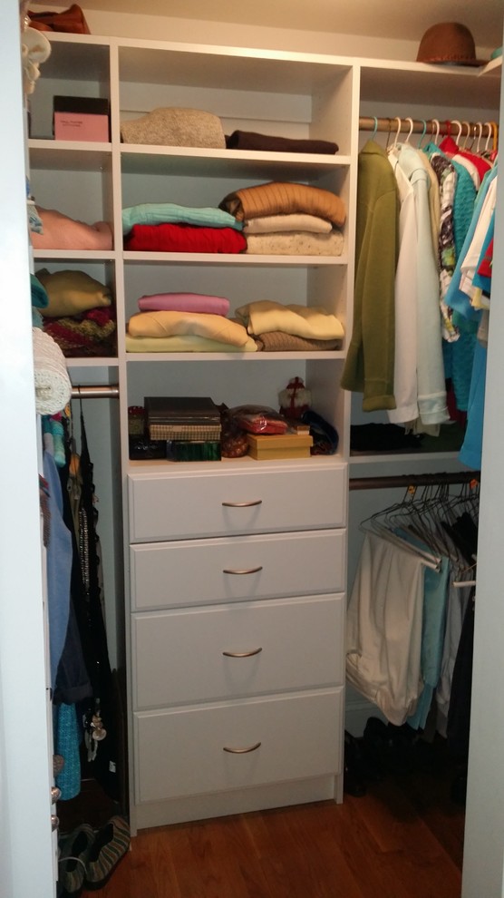 Diseño de armario vestidor clásico pequeño con armarios con paneles lisos, puertas de armario blancas y suelo de madera clara