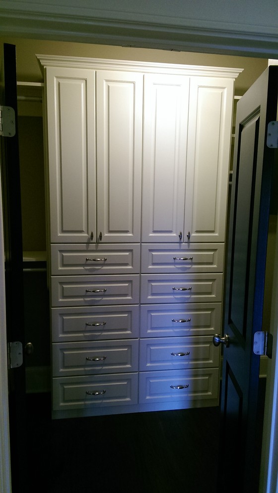 Imagen de armario vestidor unisex clásico pequeño con puertas de armario blancas, suelo de madera oscura, armarios con paneles empotrados y suelo marrón