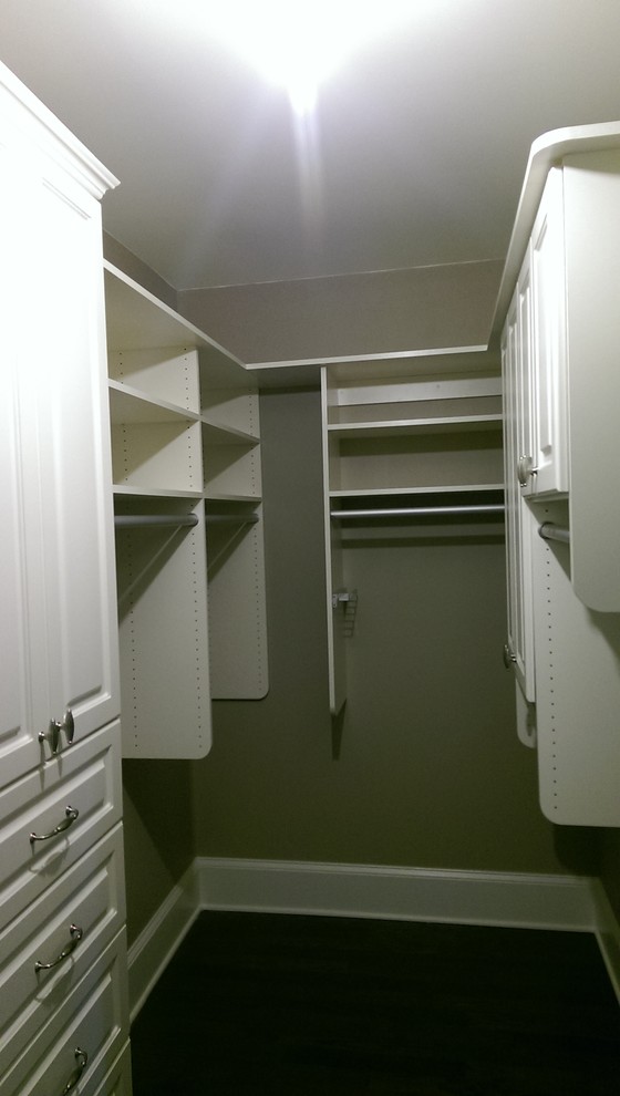 Ejemplo de armario vestidor unisex tradicional pequeño con puertas de armario blancas, suelo de madera oscura, armarios con paneles empotrados y suelo marrón