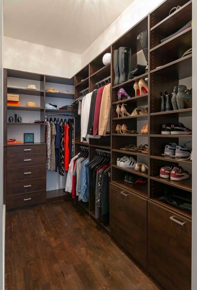 This is an example of a medium sized contemporary gender neutral walk-in wardrobe in New York with flat-panel cabinets, dark wood cabinets, medium hardwood flooring and brown floors.