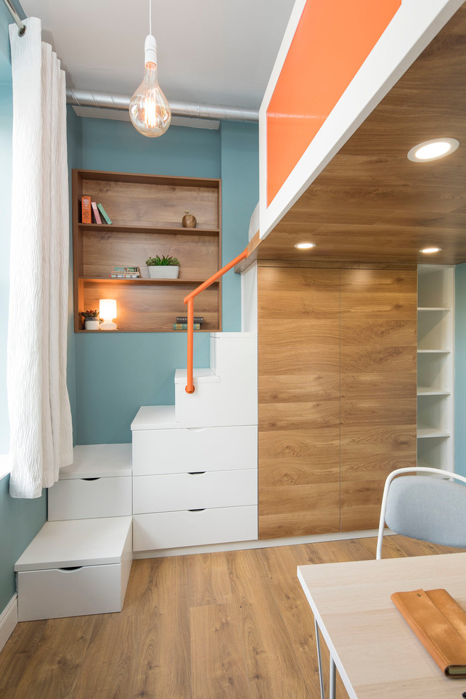 Photo of a small contemporary gender neutral standard wardrobe in Dublin with flat-panel cabinets, medium wood cabinets, laminate floors and brown floors.