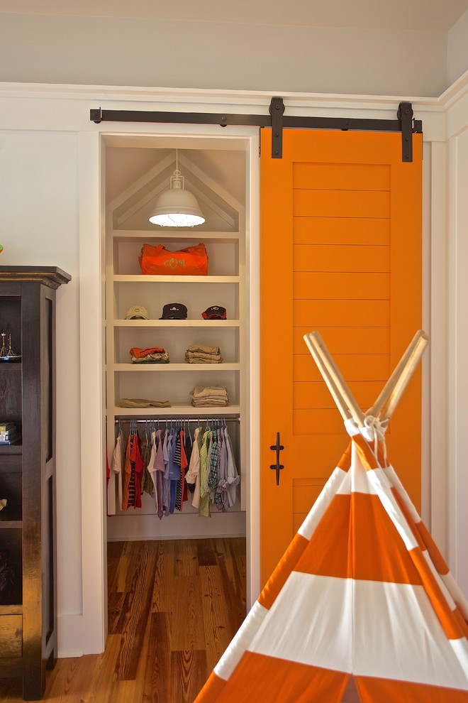 Imagen de armario y vestidor costero con puertas de armario blancas y suelo de madera en tonos medios