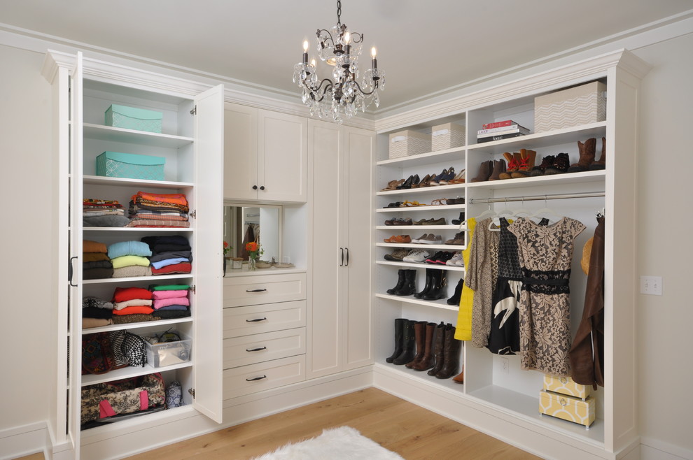 Example of a large transitional women's light wood floor walk-in closet design in New York with shaker cabinets and white cabinets