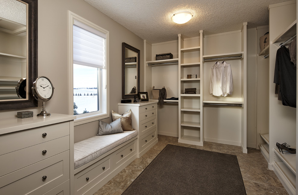 This is an example of a classic gender neutral walk-in wardrobe in Calgary with open cabinets, white cabinets and ceramic flooring.