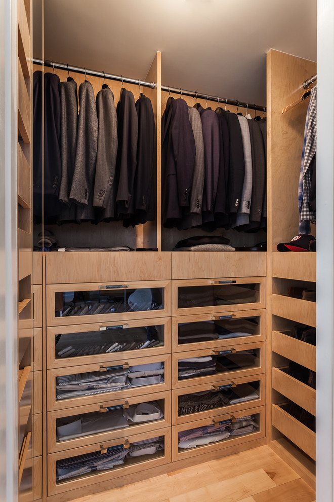 Diseño de armario vestidor unisex moderno de tamaño medio con armarios tipo vitrina, puertas de armario de madera clara y suelo de madera clara