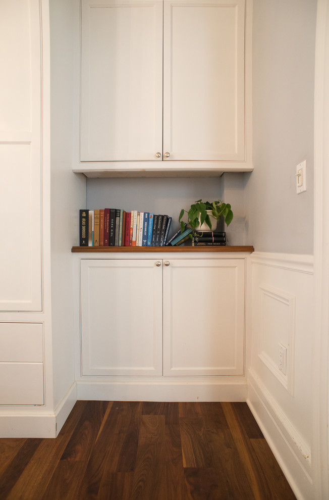 Imagen de armario clásico pequeño con armarios con paneles empotrados, puertas de armario blancas y suelo de madera en tonos medios