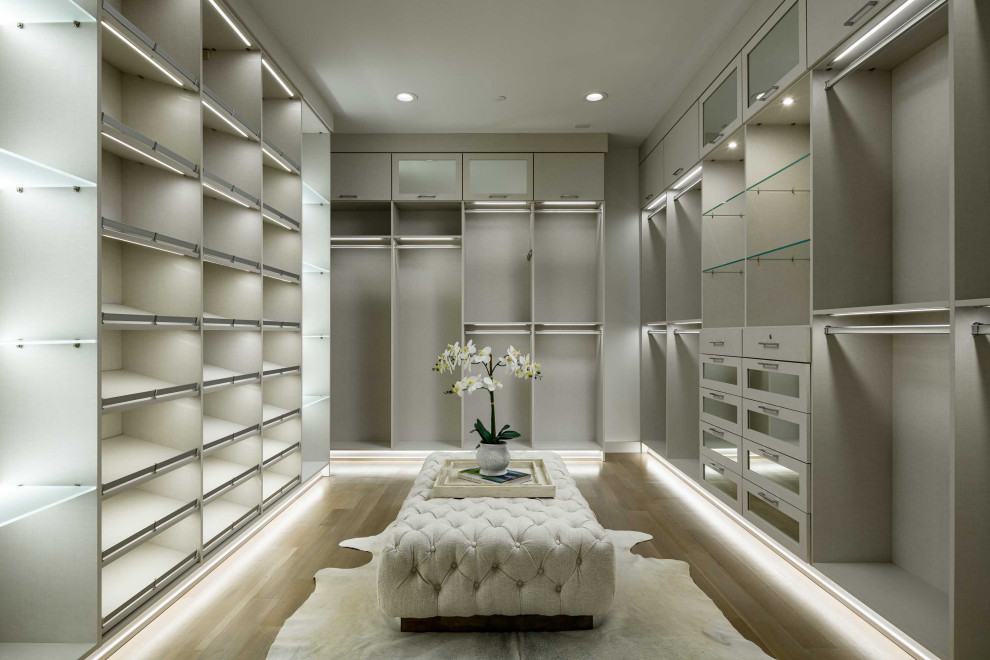 Photo of a large wardrobe in Dallas with light hardwood flooring.