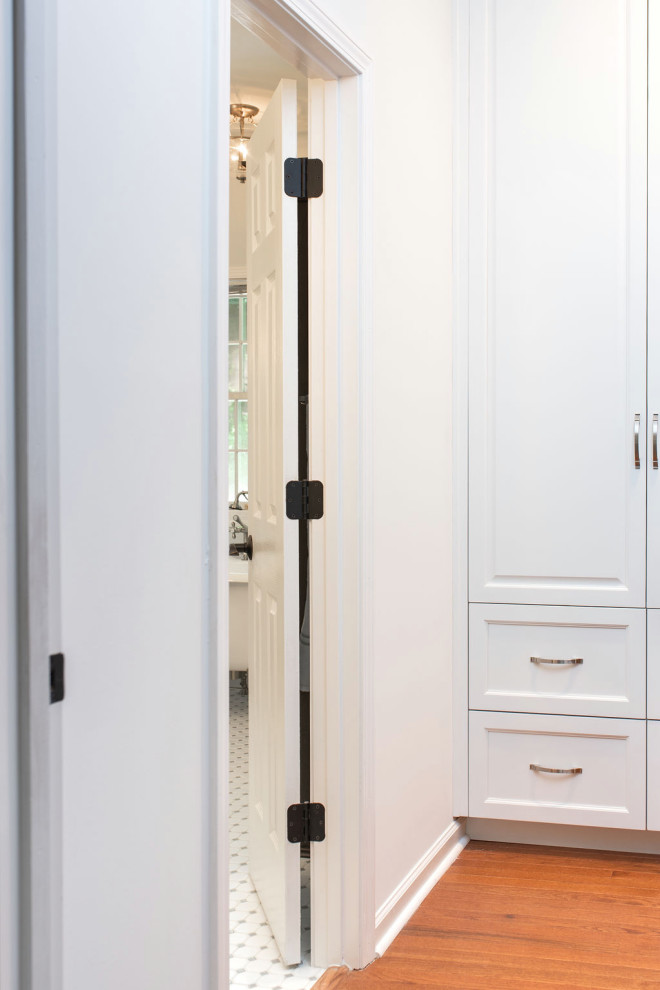 Exempel på ett mellanstort klassiskt walk-in-closet för könsneutrala, med luckor med infälld panel, vita skåp, ljust trägolv och brunt golv