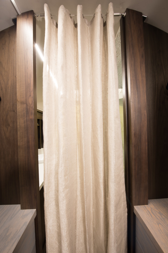Foto di un piccolo spazio per vestirsi unisex moderno con ante lisce, ante in legno bruno e pavimento in vinile